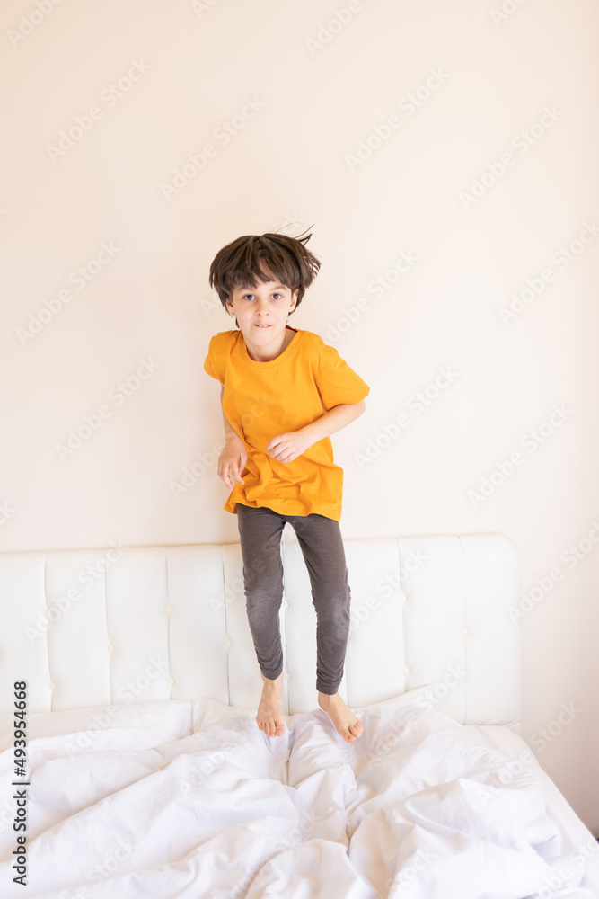 Naklejka premium An energetic child is jumping on the bed