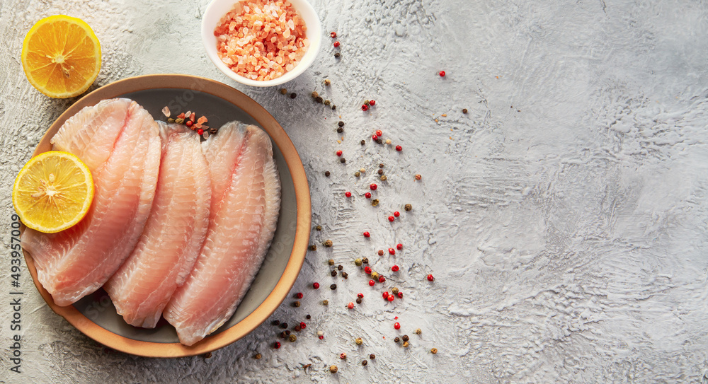Tilapia fish fillet with spices and lemon. Healthy food rich in proteins. Stock Photo Adobe Stock