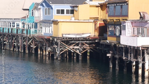 Colorful wooden houses on piles, pillars or pylons, ocean sea water, historic Old Fisherman's Wharf, Monterey bay or harbor, California coast USA. Tourist beachfront promenade, waterfront boardwalk.