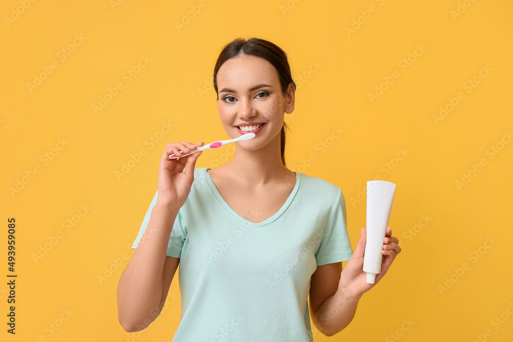 Pretty young woman with paste brushing teeth on yellow background Pretty young woman with paste brushing teeth on yellow background
