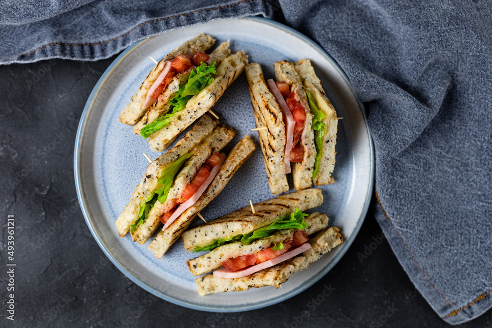 sandwich with ham cheese tomatoes lettuce onions on plate. Classic club sandwich with whole grain bread sandwich with ham cheese tomatoes lettuce onions on plate. Classic club sandwich with whole grain bread