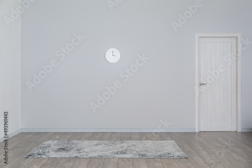 View of big empty room with hanging clock, carpet and door