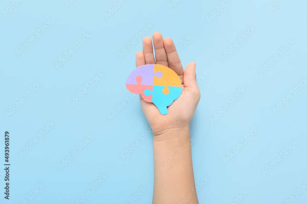 Child with paper brain on blue background. Concept of autistic disorder