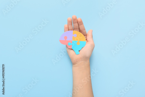 Child with paper brain on blue background. Concept of autistic disorder