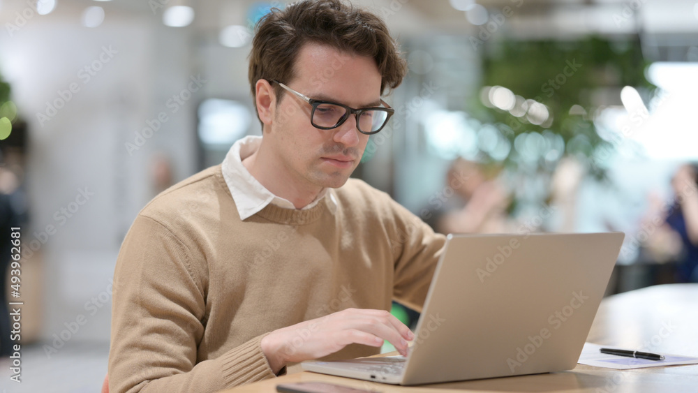 Young Man Working on Laptop in Office Young Man Working on Laptop in Office