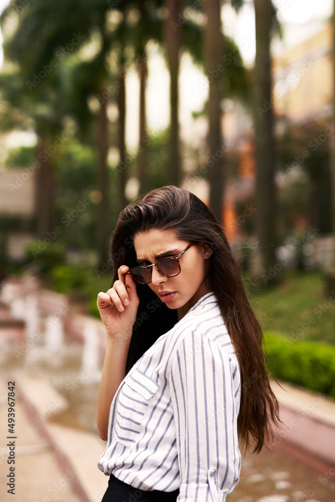 Are you following me. Cropped shot of an attractive young woman looking back while walking down the street outdoors.