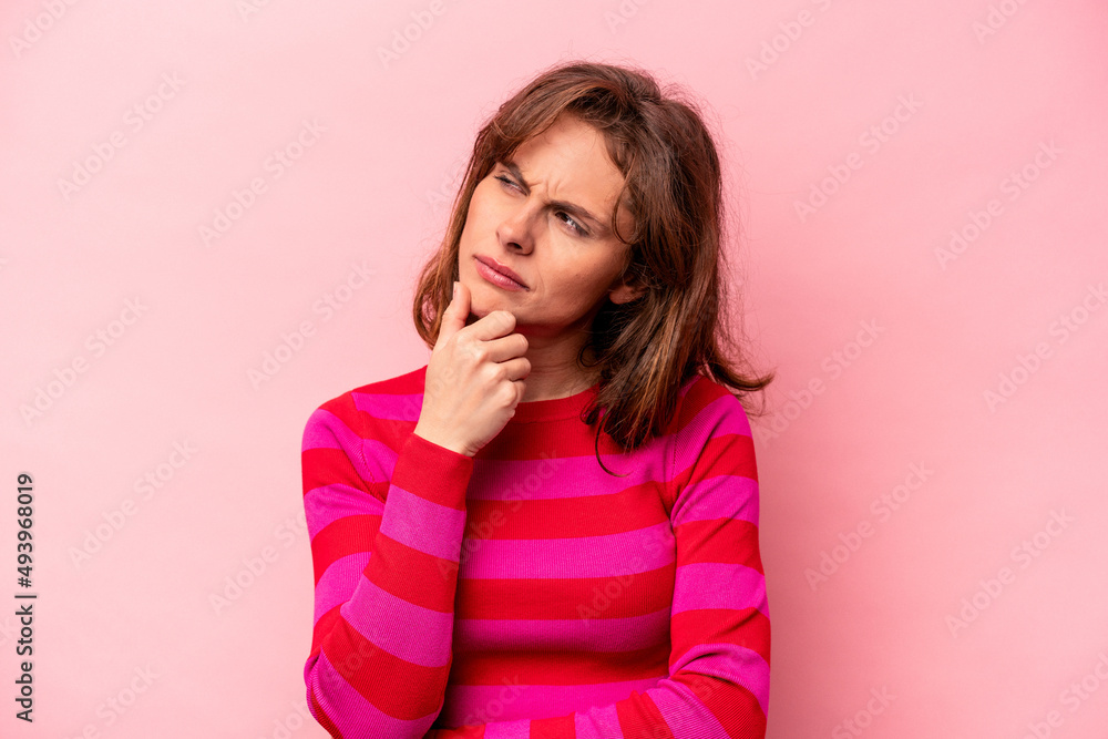 Young caucasian woman isolated on pink background thinking and looking up, being reflective, contemplating, having a fantasy. Young caucasian woman isolated on pink background thinking and looking up, being reflective, contemplating, having a fantasy.