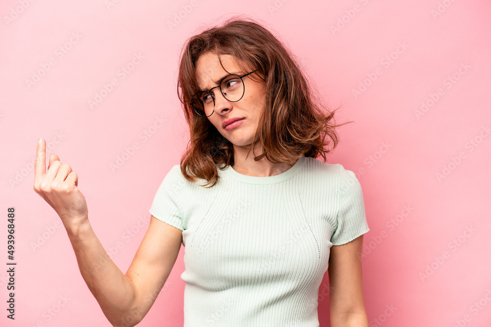Young caucasian woman isolated on pink background pointing with finger at you as if inviting come closer. Young caucasian woman isolated on pink background pointing with finger at you as if inviting come closer.