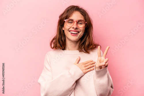 Young caucasian woman isolated on pink background taking an oath, putting hand on chest.