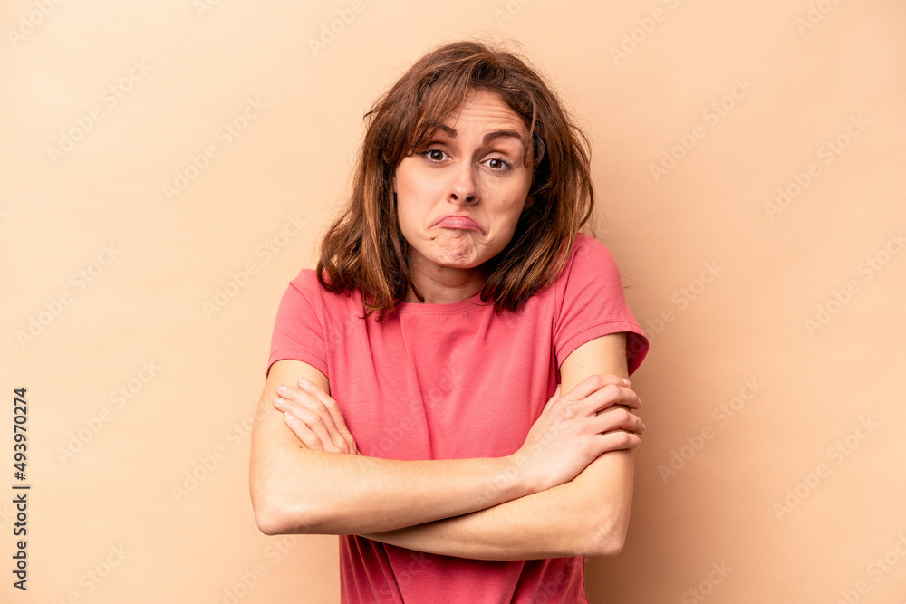 Young caucasian woman isolated on beige background shrugs shoulders and open eyes confused. Young caucasian woman isolated on beige background shrugs shoulders and open eyes confused.