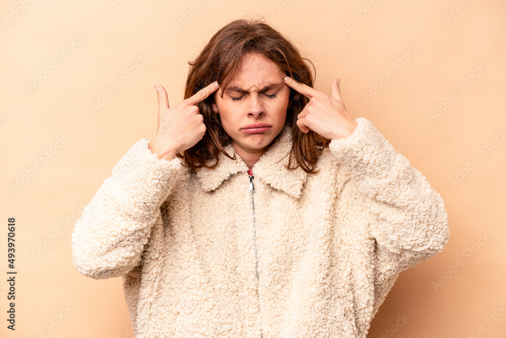 Young caucasian woman isolated on beige background focused on a task, keeping forefingers pointing head. Young caucasian woman isolated on beige background focused on a task, keeping forefingers pointing head.