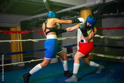 Strong boxer girls boxing on ring in sport center. Two healthy young girls in sportswear fighting, practicing attack punches, preparing for great competition. Healthy lifestyle, womens boxing concept