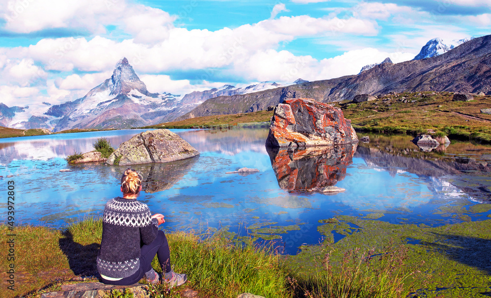 Scenic landscape in the Swiss Alps with a girl who looks at the top of the mountain Matterhorn near the Lake Stelliseenear Zermatt.