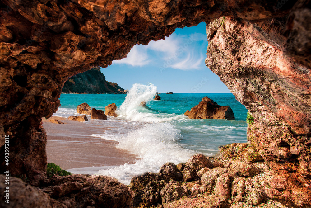 Beautiful magical view of the beach with heavy waves through a hole in the rock