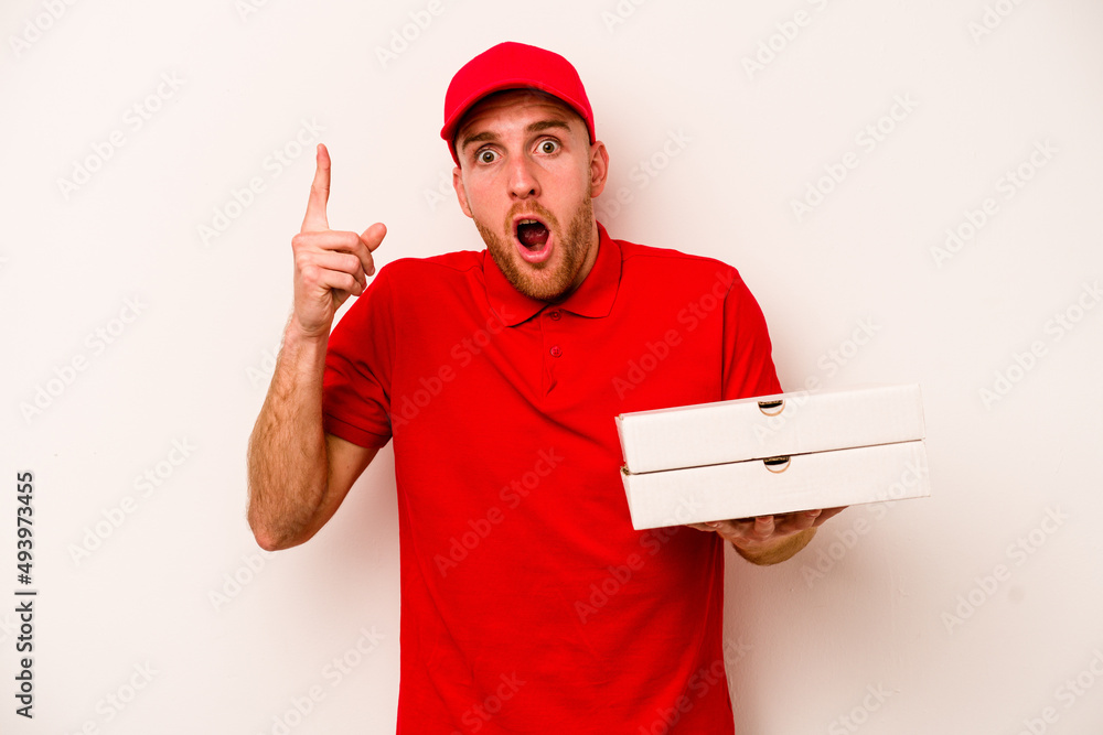 Young delivery caucasian man holding pizzas isolated on white background having an idea, inspiration concept. Young delivery caucasian man holding pizzas isolated on white background having an idea, inspiration concept.