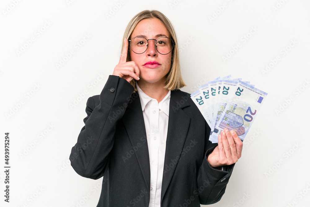 Young business caucasian woman holding banknotes isolated on white background pointing temple with finger, thinking, focused on a task. Young business caucasian woman holding banknotes isolated on white background pointing temple with finger, thinking, focused on a task.