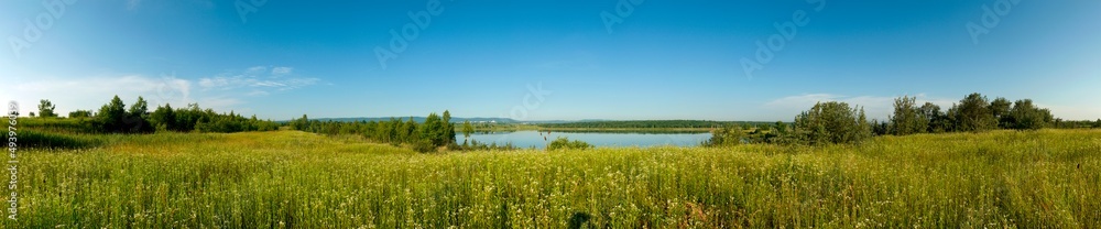 Panorama of wildflowers and lakes, blue sky, cloudless horizon.