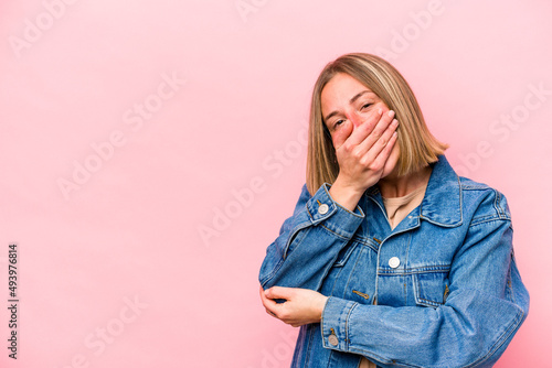 Young caucasian woman isolated on pink background laughing happy, carefree, natural emotion.