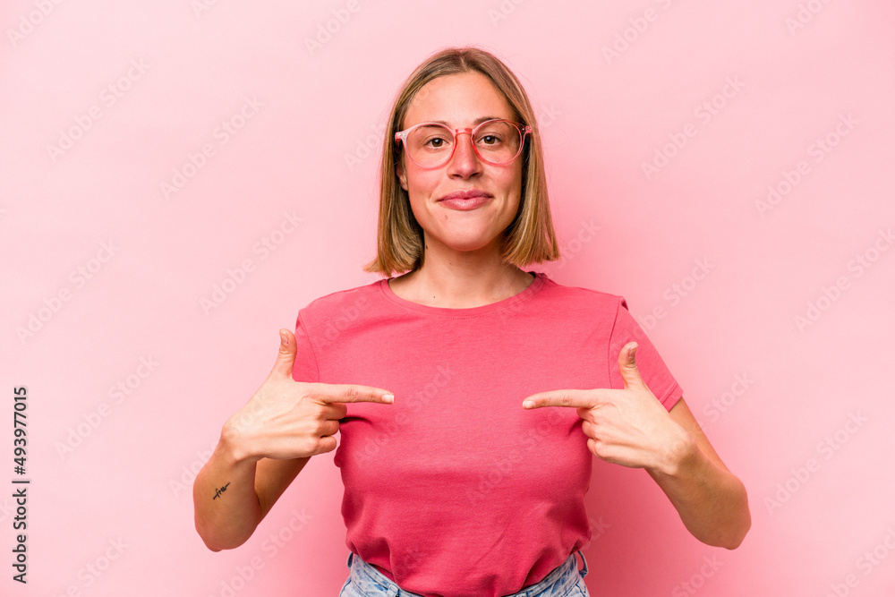 Young caucasian woman isolated on pink background person pointing by hand to a shirt copy space, proud and confident Young caucasian woman isolated on pink background person pointing by hand to a shirt copy space, proud and confident