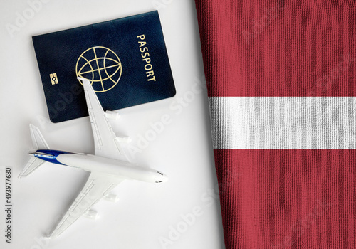 Flag of Latvia with passport and toy airplane. Flight travel concept 