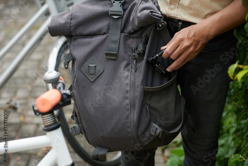 Closeup image of bicycle rider putting lock in pocket of backpack for security