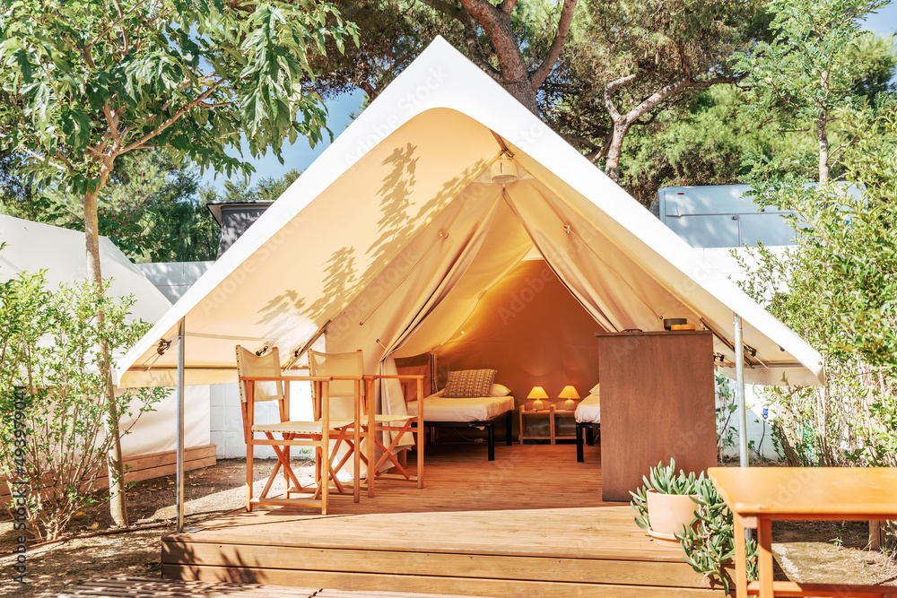 Glamping open tent with cozy interior on a sunny day. Luxury camping tent for outdoor summer holiday and vacation. Lifestyle concept - obrazy, fototapety, plakaty 