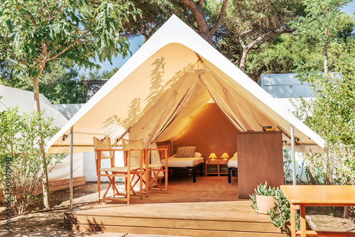 Glamping open tent with cozy interior on a sunny day. Luxury camping tent for outdoor summer holiday and vacation. Lifestyle concept © AdriaVidal
