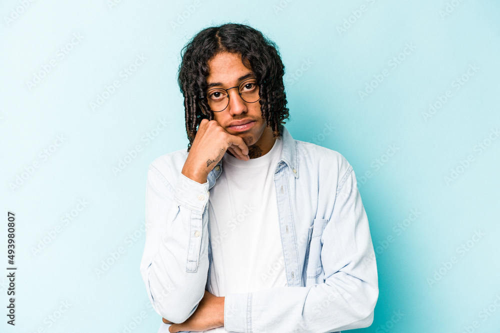 Young African American man isolated on blue background tired of a repetitive task. Young African American man isolated on blue background tired of a repetitive task.