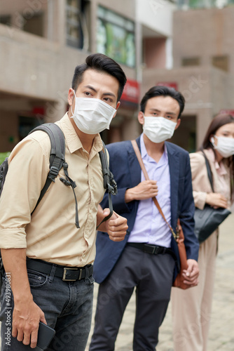 Business people in medical masks trying to catch taxi car outdoors