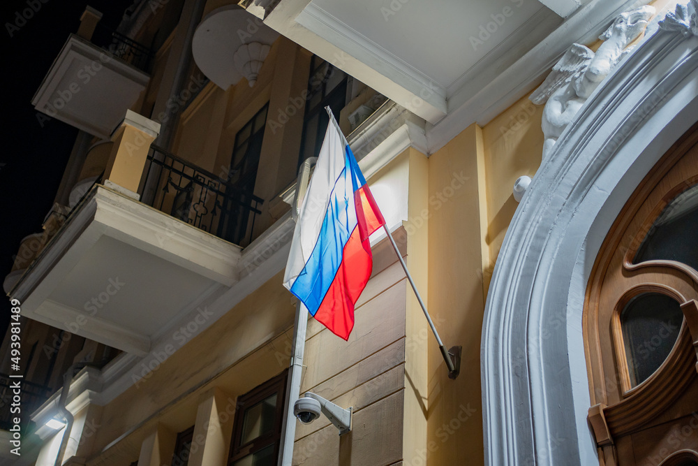 the flag of the Russian Federation develops in the wind at night on the administrative building. international relations and crisis. state symbols.