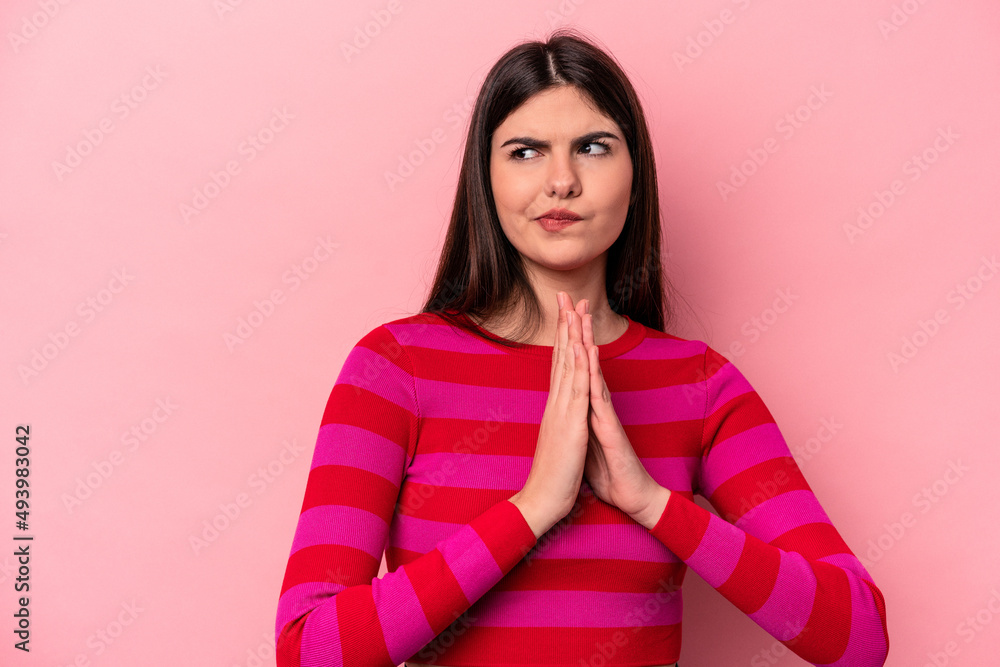 Young caucasian woman isolated on pink background praying, showing devotion, religious person looking for divine inspiration. Young caucasian woman isolated on pink background praying, showing devotion, religious person looking for divine inspiration.