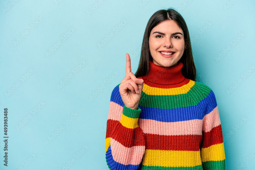 Young caucasian woman isolated on blue background showing number one with finger. Young caucasian woman isolated on blue background showing number one with finger.