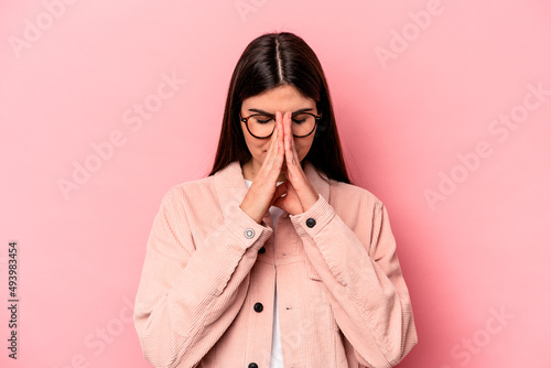 Young caucasian woman isolated on pink background praying, showing devotion, religious person looking for divine inspiration.