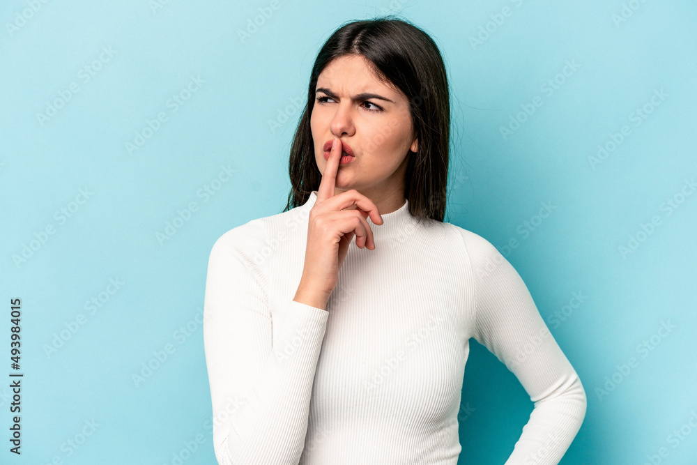 Young caucasian woman isolated on blue background keeping a secret or asking for silence. Young caucasian woman isolated on blue background keeping a secret or asking for silence.