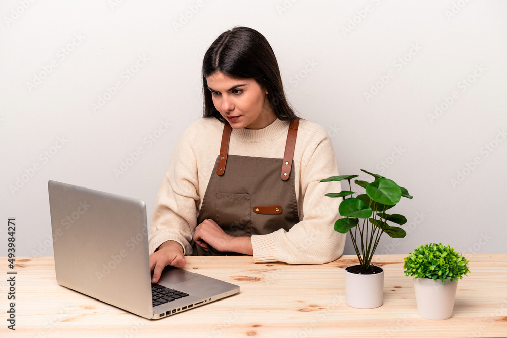 Young caucasian gardener woman working on the table isolated on white background