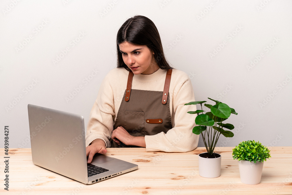 Young caucasian gardener woman working on the table isolated on white background Young caucasian gardener woman working on the table isolated on white background