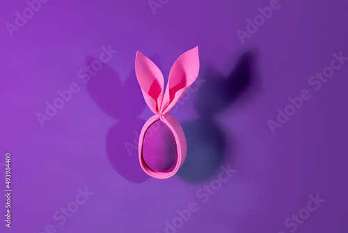 Foam pink egg with rabbit ears in neon holographic violet light. Creative Easter handmade concept. © Ekaterina