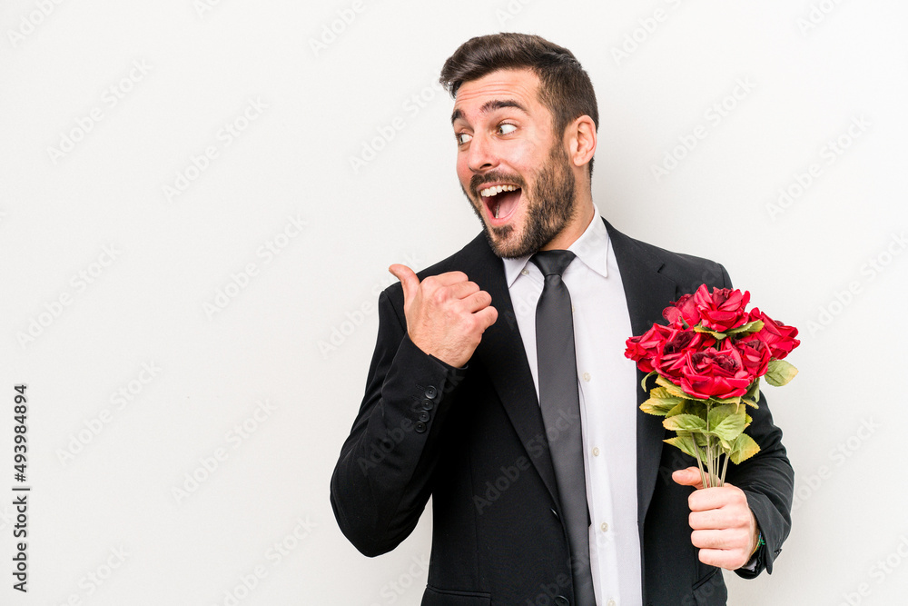 Young caucasian man holding a bouquet of flowers isolated on white background points with thumb finger away, laughing and carefree. Young caucasian man holding a bouquet of flowers isolated on white background points with thumb finger away, laughing and carefree.