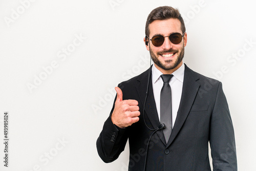 Young caucasian bodyguard man isolated on white background smiling and raising thumb up photo
