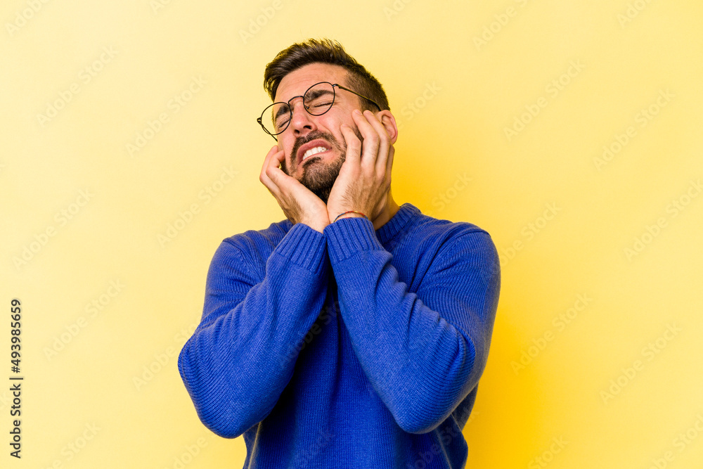 Young caucasian man isolated on yellow background crying, unhappy with something, agony and confusion concept. Young caucasian man isolated on yellow background crying, unhappy with something, agony and confusion concept.