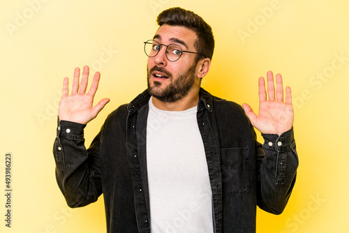Young caucasian man isolated on yellow background being shocked due to an imminent danger © Asier