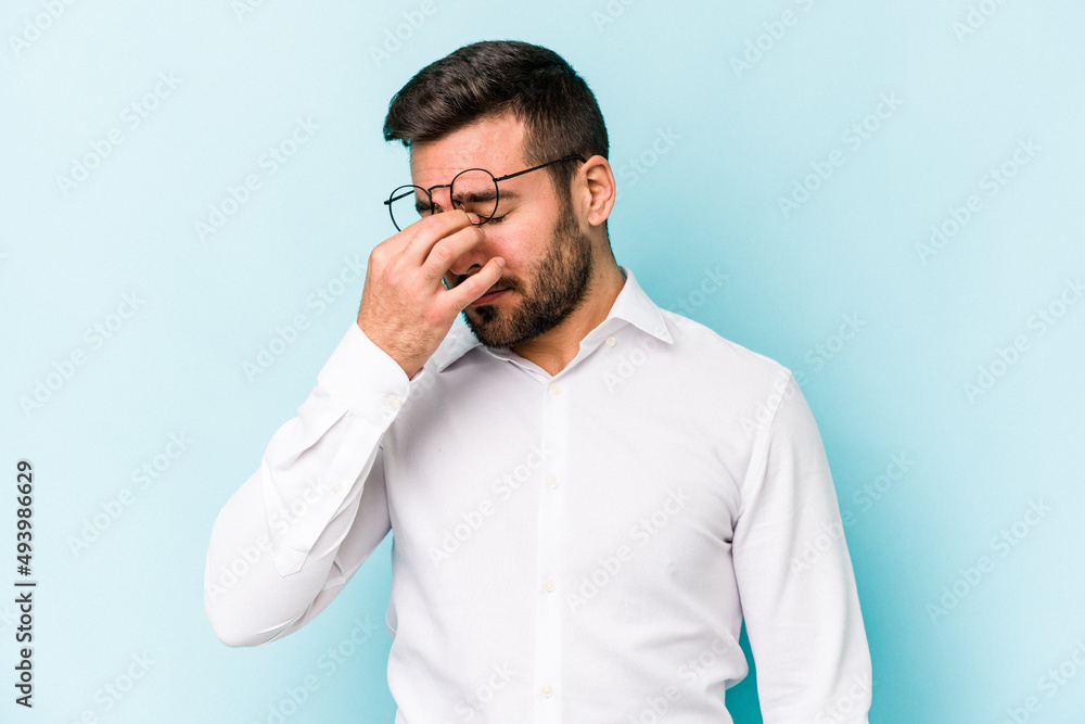 Young caucasian man isolated on blue background having a head ache, touching front of the face. Young caucasian man isolated on blue background having a head ache, touching front of the face.