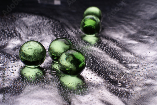 Closeup of a green orbeez on a wet silver surface photo