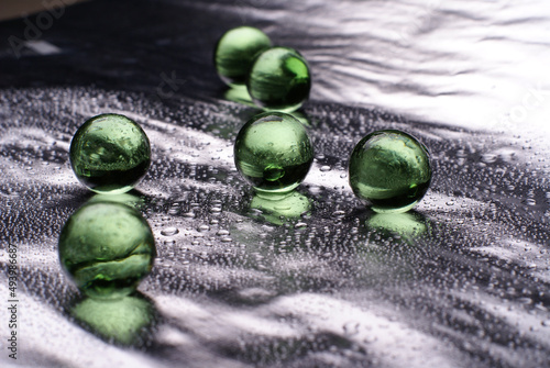 Closeup of a green orbeez on a wet silver surface photo