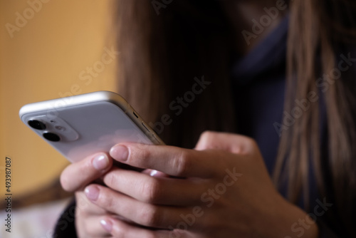 Phone in female hands on a yellow background close-up