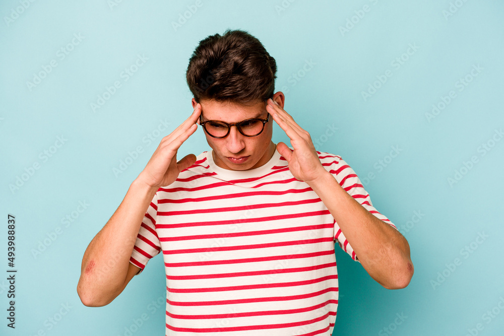 Young caucasian man isolated on blue background touching temples and having headache. Young caucasian man isolated on blue background touching temples and having headache.