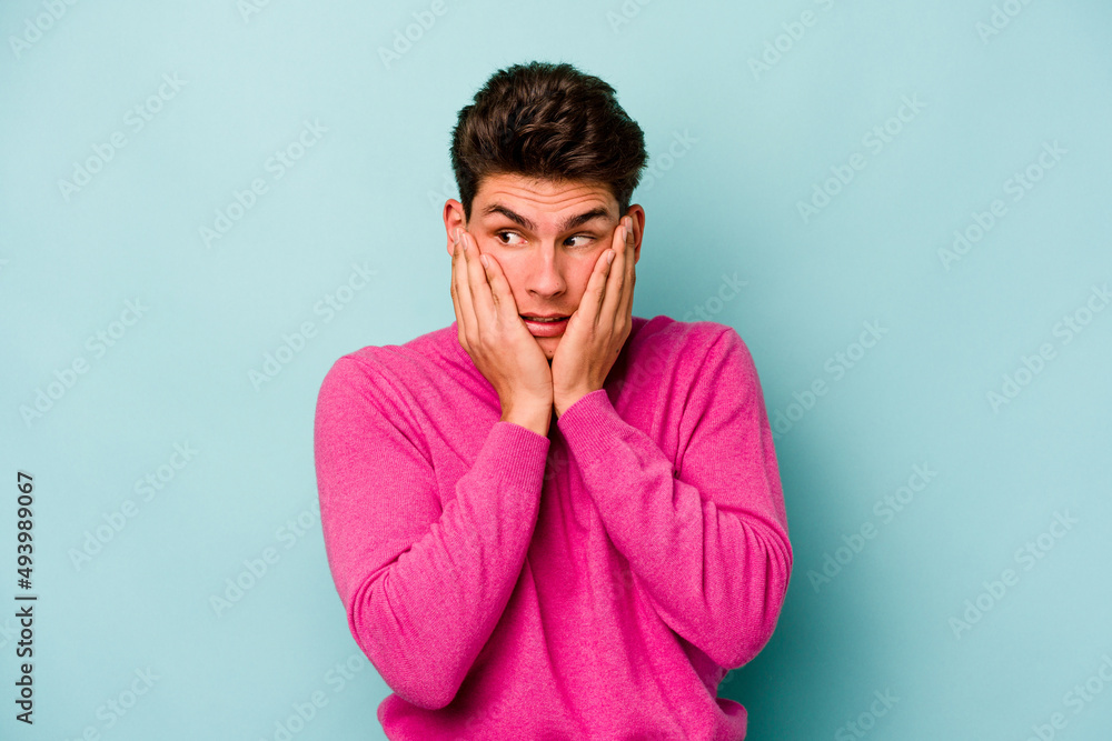 Fototapeta premium Young caucasian man isolated on blue background scared and afraid.
