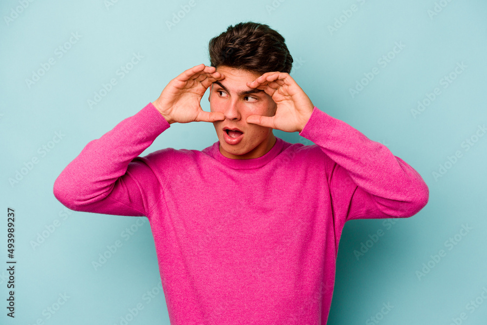 Young caucasian man isolated on blue background keeping eyes opened to find a success opportunity. Young caucasian man isolated on blue background keeping eyes opened to find a success opportunity.