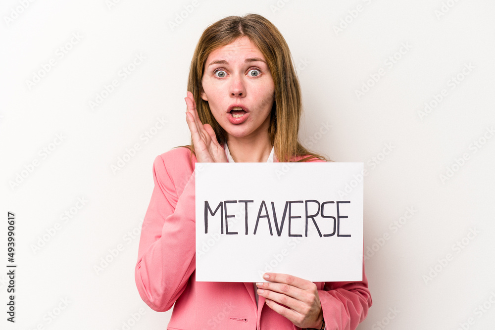 Young English business woman holding a metaverse placard isolated on white background surprised and shocked. Young English business woman holding a metaverse placard isolated on white background surprised and shocked.