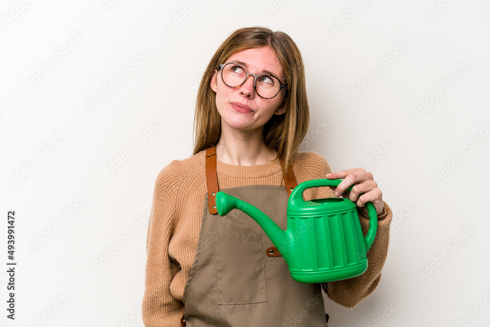 Young gardener woman holding a sprinkler isolated on white background dreaming of achieving goals and purposes Young gardener woman holding a sprinkler isolated on white background dreaming of achieving goals and purposes